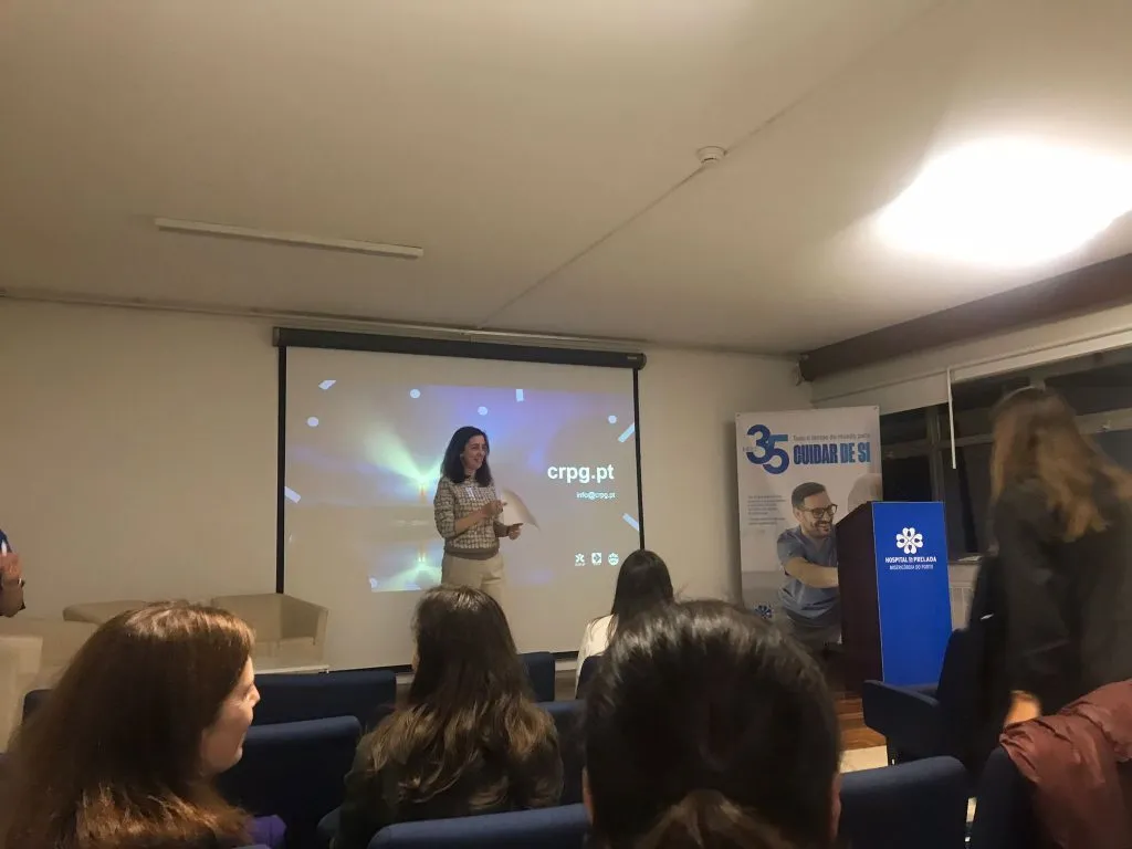 fotografia de pessoa a realizar apresentação no palco e pessoas a assistir