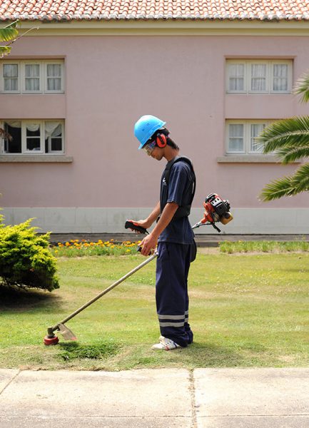 homem a trabalhar com motorroçadora, com equipamentos de proteção individual