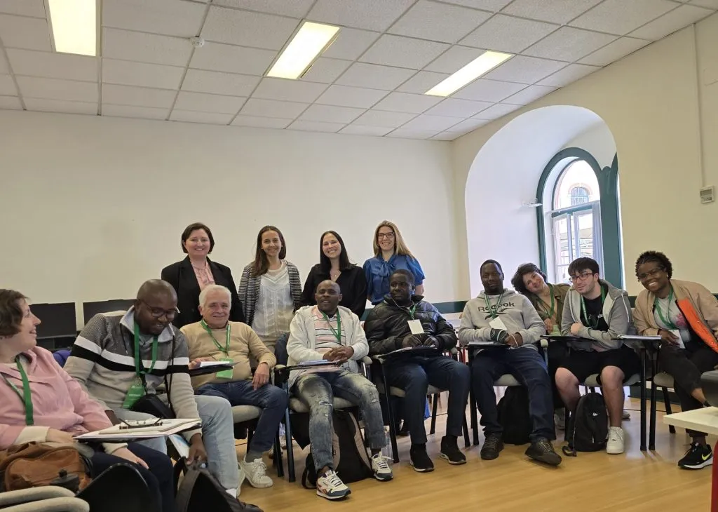 fotografia de grupo de pessoas sentadas a olhar para a camera