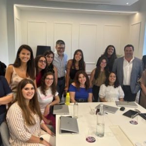 Fotografia de pessoas numa sala de reuniões, alguns sentados e outros em pé, a olharem para a fotografia