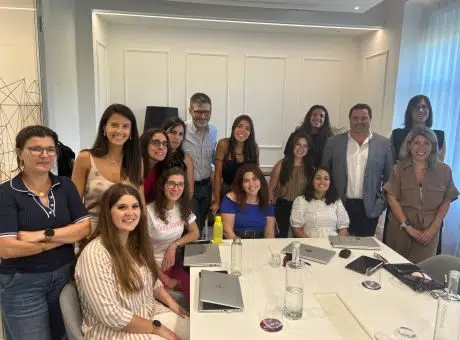 Fotografia de pessoas numa sala de reuniões, alguns sentados e outros em pé, a olharem para a fotografia