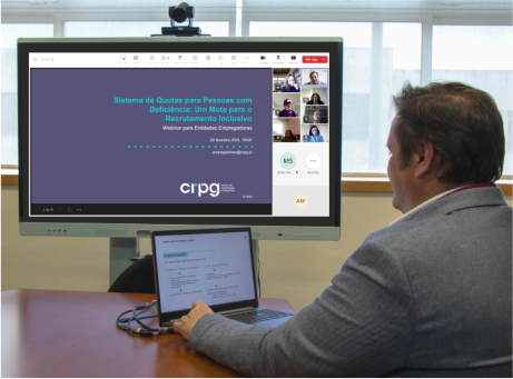 pessoa sentada numa mesa com um computador durante um webinar