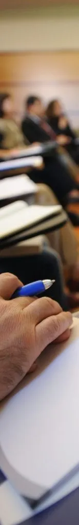 caneta na mão pousada num caderno durante uma aula