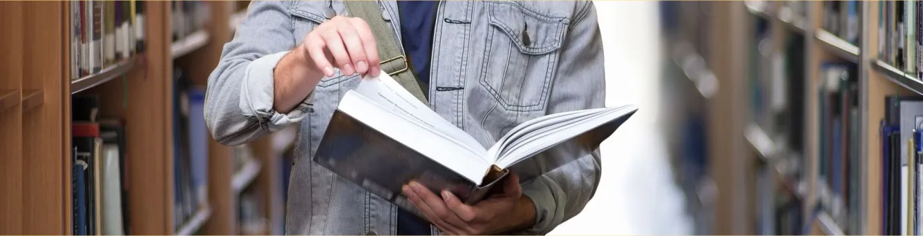 pessoa em pé a ler um livro na biblioteca