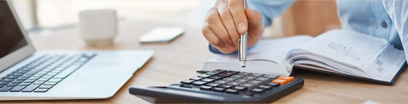 pessoa com caneta na mão a fazer contas na calculadora