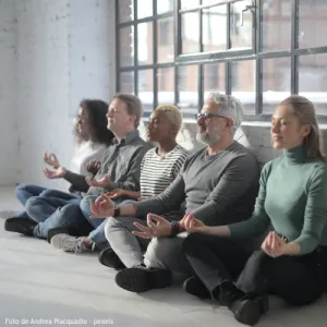 Grupo de 5 pessoas sentadas no chão a meditar.