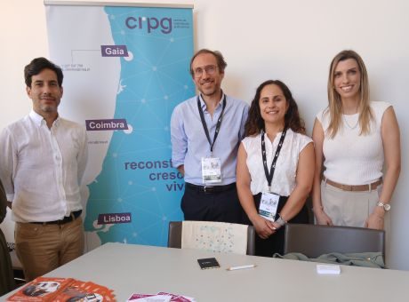 4 colaboradores do CRPG, em pé, lado a lado a olhar para a fotografia com um roll up do CRPG atrás