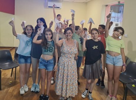 fotografia de alunos a sorrir para a fotografia, com aviões de papel na mão