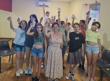 fotografia de alunos a sorrir para a fotografia, com aviões de papel na mão