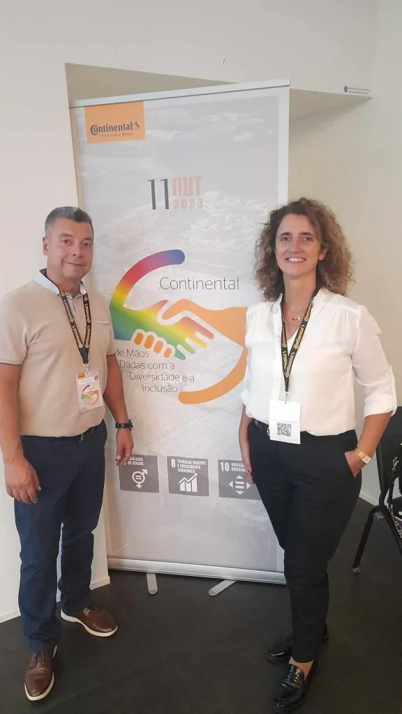 fotografia de dois participantes no evento com roll up no fim