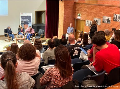 fotografia de pessoas a assistir a conversa no palco