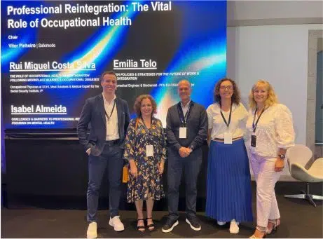 fotografia de 4 oradores, lado a lado, no palco com um ecrã atrás com o titulo da apresentação