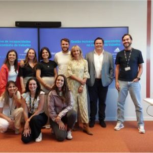 Fotografia de grupo de pessoas a sorrirem para a fotografia com a apresentação da formação no ecrã