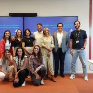Fotografia de grupo de pessoas a sorrirem para a fotografia com a apresentação da formação no ecrã
