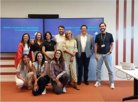 Fotografia de grupo de pessoas a sorrirem para a fotografia com a apresentação da formação no ecrã