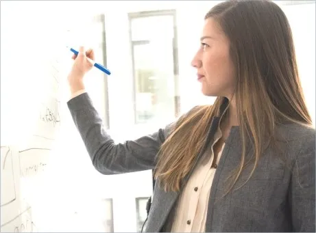 Mulher a escrever em quadro branco, com caneta de feltro