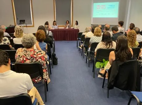 fotografia de plateia a olhar para pessoas sentadas numa mesa a fazer uma apresentação