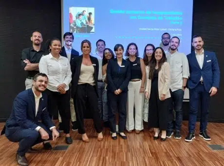 Grupo de pessoas, em pé, lado a lado, a olhar para a fotografia. Nas suas costas a apresentação da formação projetada.