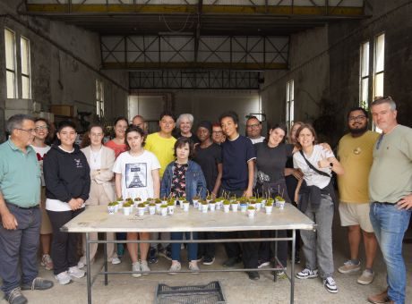 grupo de alunos lado a lado a olhar para a fotografia com uma mesa à frente e arranjos com plantas realizados pelos próprios