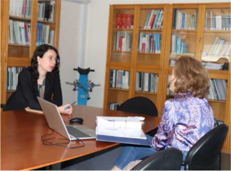 fotografia de Joelma Santos a conversar com técnica do CRPG, sentadas à mesa, em sala de reunião