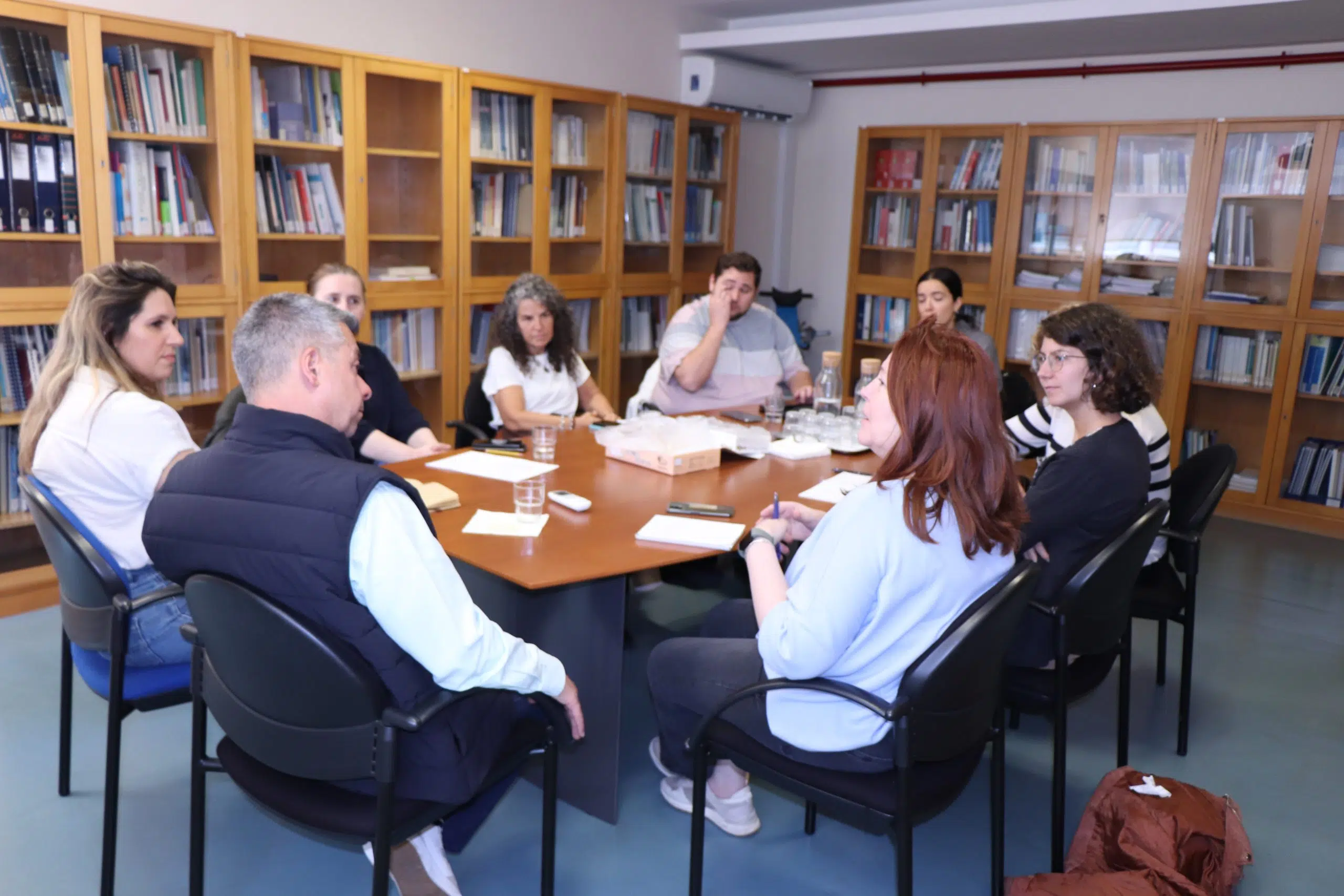 9 pessoas à mesa durante reunião