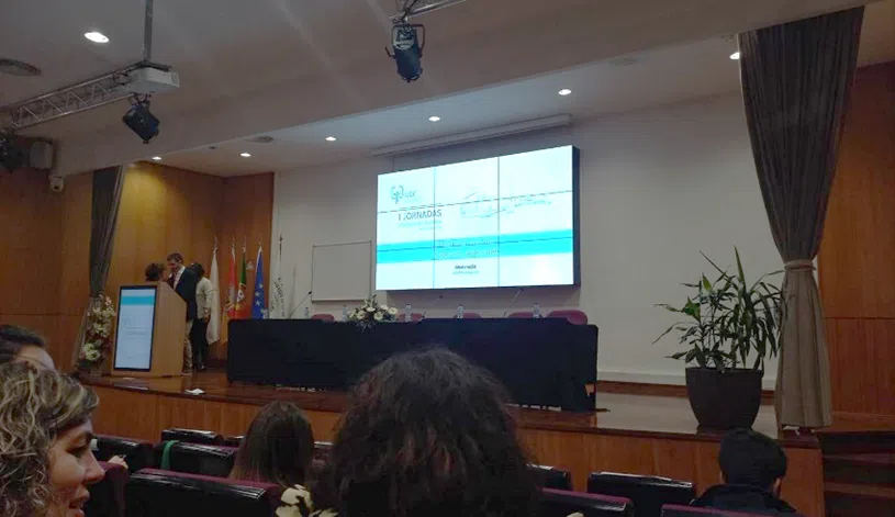 fotografia do palco das I Jornadas da Unidade de Cuidados Continuados. Ecrã com apresentação e pessoas no púlpito a preparar comunicação.