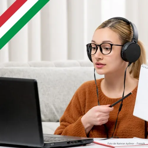 Rapariga à secretária, a olhar para portátil, com lápis e caderno nas mãos.