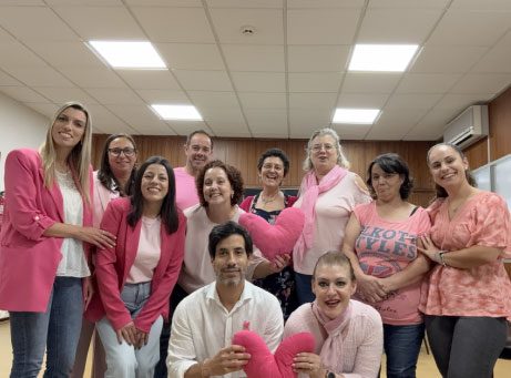 fotografia de grupo de pessoas, com uma peça de roupa rosa vestida a sorrir para a fotografia