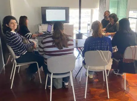 fotografia de grupo de pessoas, sentadas à mesa, no formato U, durante a reunião