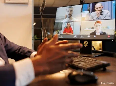 fotografia de pessoa à secretaria durante uma sessão online, com o teclado e monitor à sua frente