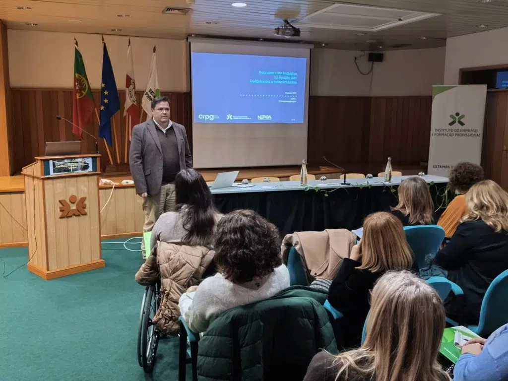 grupo de pessoas sentadas a assistir a apresentação de orador em pé à frente