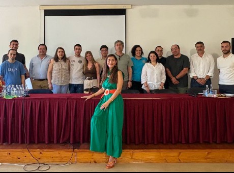 fotografia de grupo de pessoas, lado a lado, em pé, a sorrirem para a fotografia, atrás de uma mesa comprida com uma tolha bordeaux