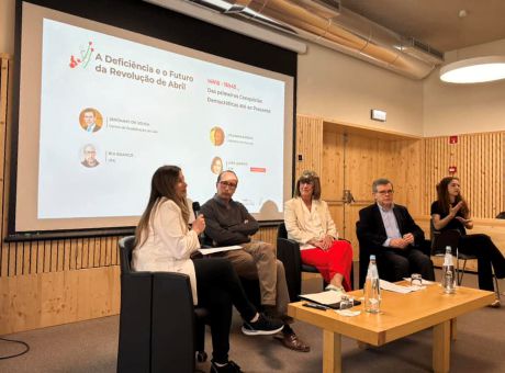 fotografia de oradores sentados lado a lado, durante a sua participação