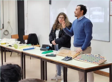 pessoa em pé, atrás de uma mesa a fazer uma apresentação