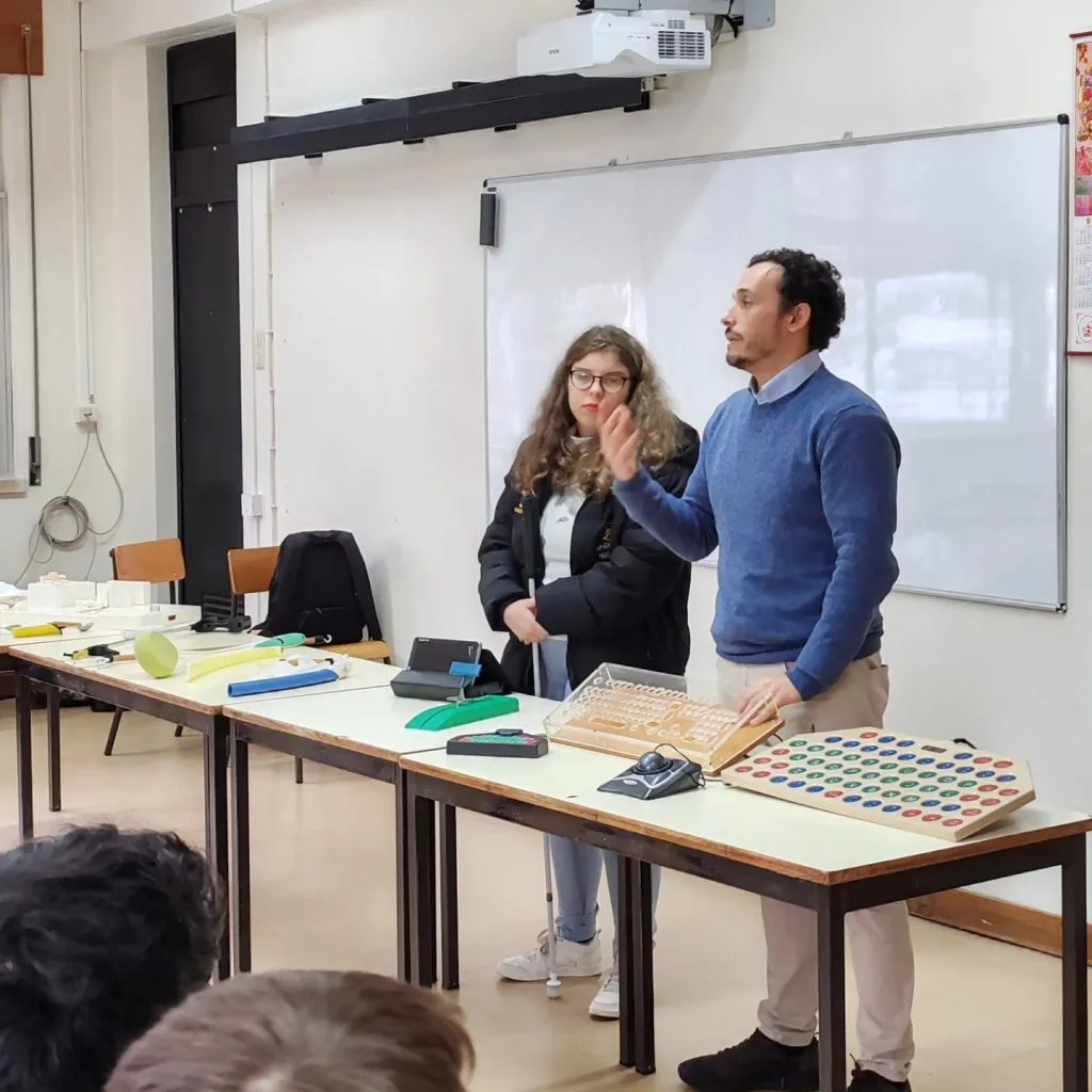 pessoa em pé, atrás de uma mesa a fazer uma apresentação