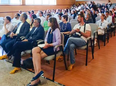 fotografia de pessoas sentadas em auditório a assistir a apresentação que decorre no palco