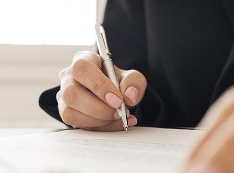 Caneta na mão a assinar um documento