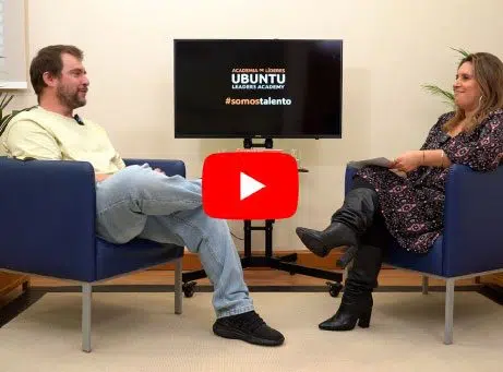 imagem do vídeo parado, duas pessoas sentadas frente a frente a conversar, com simbolo do youtube no centro